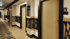Un couloir d’hôtel avec les portes numérotées 122 et 124, présentant un design moderne avec des motifs géométriques et un sol recouvert de moquette.