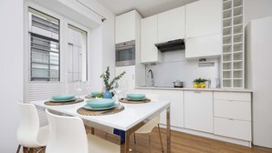 A modern kitchen with white cabinetry, a built-in oven, and a stainless steel range hood.