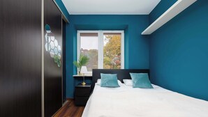 A bedroom with a large bed, a nightstand, a window, and a view of trees.