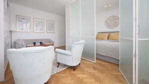 Un dormitorio moderno con un armario grande, una cama con cubrecama acolchado y una zona de estar con sofá y sillones.