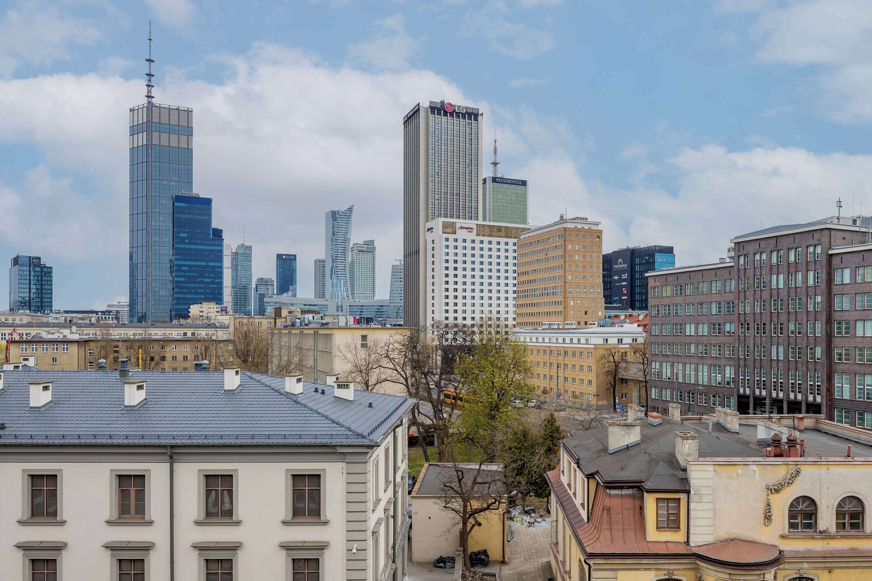 Un paysage urbain avec des gratte-ciel modernes, des bâtiments plus anciens et un ciel dégagé.