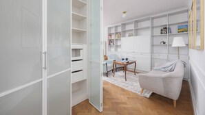 Una sala moderna con un sofá blanco, una mesa de centro de madera y un armario con puerta de vidrio.
