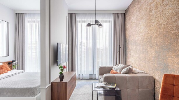 Una habitación de hotel moderna con una cama, un sofá, una mesita de café y un televisor.