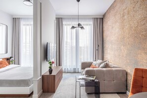 Une chambre d’hôtel moderne équipée d’un lit, d’un canapé, d’une table basse et d’un téléviseur.