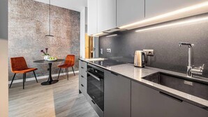 Una cocina moderna con horno empotrado, un lavamanos y una mesa de comedor redonda con dos sillas.