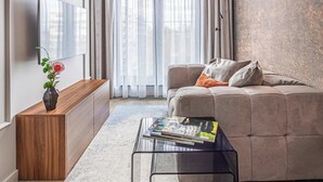 Una sala de estar moderna con un sofá, una mesa de centro, un televisor y un ventanal con cortinas.