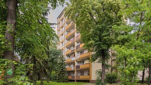 A multi-story residential building with balconies, surrounded by trees and greenery. - Stylish Apartment in Warsaw | Smart TV and Workspace (Warszawa)