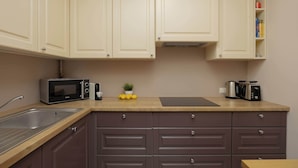 A kitchen with light-colored cabinets, a stainless steel sink, a microwave, a toaster, and a small potted plant on the counter. - Stylish Apartment in Warsaw | Smart TV and Workspace (Warszawa)