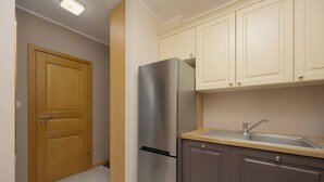 A kitchen with a stainless steel refrigerator, wooden cabinets, and a sink. - Stylish Apartment in Warsaw | Smart TV and Workspace (Warszawa)