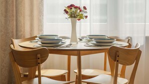 A dining area with a round wooden table, six chairs, and a vase with flowers. - Stylish Apartment in Warsaw | Smart TV and Workspace (Warszawa)
