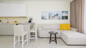 A modern living room with a sofa, a dining area with a table and chairs, and a kitchen with cabinets. - Bright Apartment in the Center | Parking Space (Warszawa)