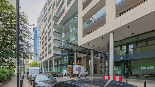 A modern building with multiple floors, large windows, and a covered entrance area. - Bright Apartment in the Center | Parking Space (Warszawa)