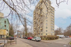 Un edificio residencial de varios pisos con balcones, coches aparcados y cielo despejado.