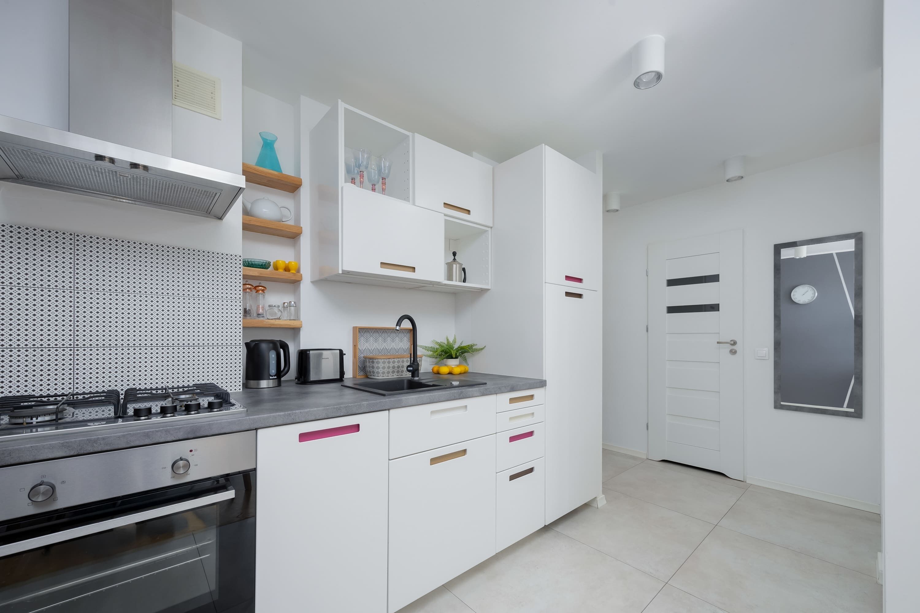 Una cocina moderna con armarios blancos, una estufa de acero inoxidable y un lavamanos.