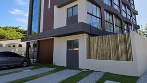 Un immeuble moderne à plusieurs étages, doté d’un toit plat, de grandes fenêtres et d’une entrée sécurisée par un portail.