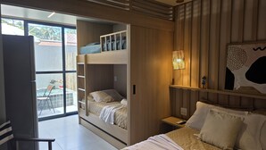Une chambre d’hôtel moderne équipée d’un lit superposé, d’un bureau, d’une chaise et d’une grande fenêtre donnant sur l’extérieur.
