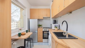 A compact kitchen with wooden cabinets, a built-in oven, a microwave, a sink, and a window providing natural light.