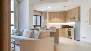 A modern living room with a sofa, a coffee table, and a kitchen area in the background.
