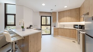 A modern kitchen with wooden cabinets, a white countertop, and stainless steel appliances.