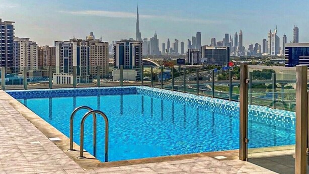A rooftop pool with a city skyline view, including a prominent skyscraper.
