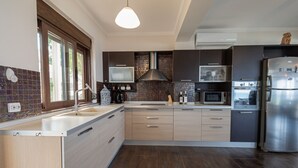 A modern kitchen with a central island, built-in appliances, and a large window.
