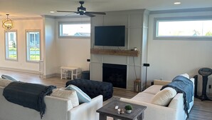 Un salon spacieux doté d’une cheminée, de deux canapés, d’une table basse et d’un ventilateur de plafond.