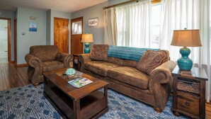 Ein Wohnzimmer mit einem braunen Ledersofa, einem Holztisch und einem blau gemusterten Teppich.