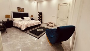 A bedroom with a bed, bedside tables, a desk, a chair, a bookshelf, and a door.