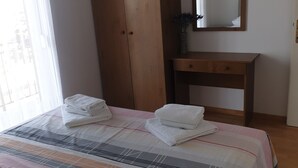 A bedroom with a bed, a wooden wardrobe, a bedside table, and a mirror.