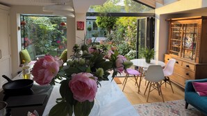 Une cuisine moderne avec un coin repas, une table décorée de fleurs et une vue sur un jardin.