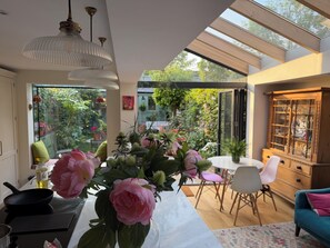 Eine moderne Küche mit Essbereich, einem Tisch mit Blumen und Blick auf einen Garten.