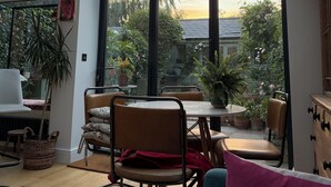 Une pièce dotée d’une grande fenêtre, d’une table, de chaises et de plantes en pot.