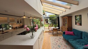 Une cuisine moderne dotée d’un îlot central, d’un coin repas avec une table et des chaises, et d’un espace salon confortable avec un canapé.