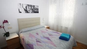 A bedroom with a bed, a nightstand, a potted plant, and a tiger artwork on the wall.