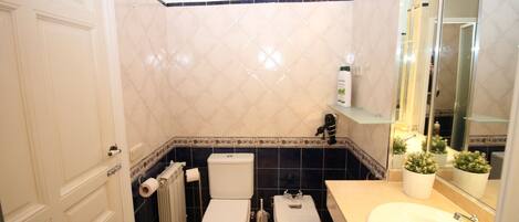 A bathroom with two toilets, a sink, and a mirror.