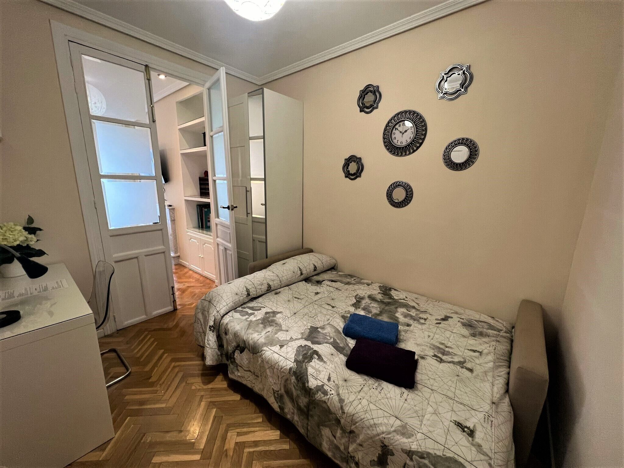 Een slaapkamer met een bed, een garderobe en een spiegel aan de muur.