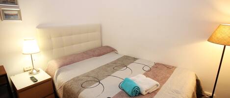 A neatly made bed with a striped bedspread, a bedside lamp, and a folded towel on the bed.