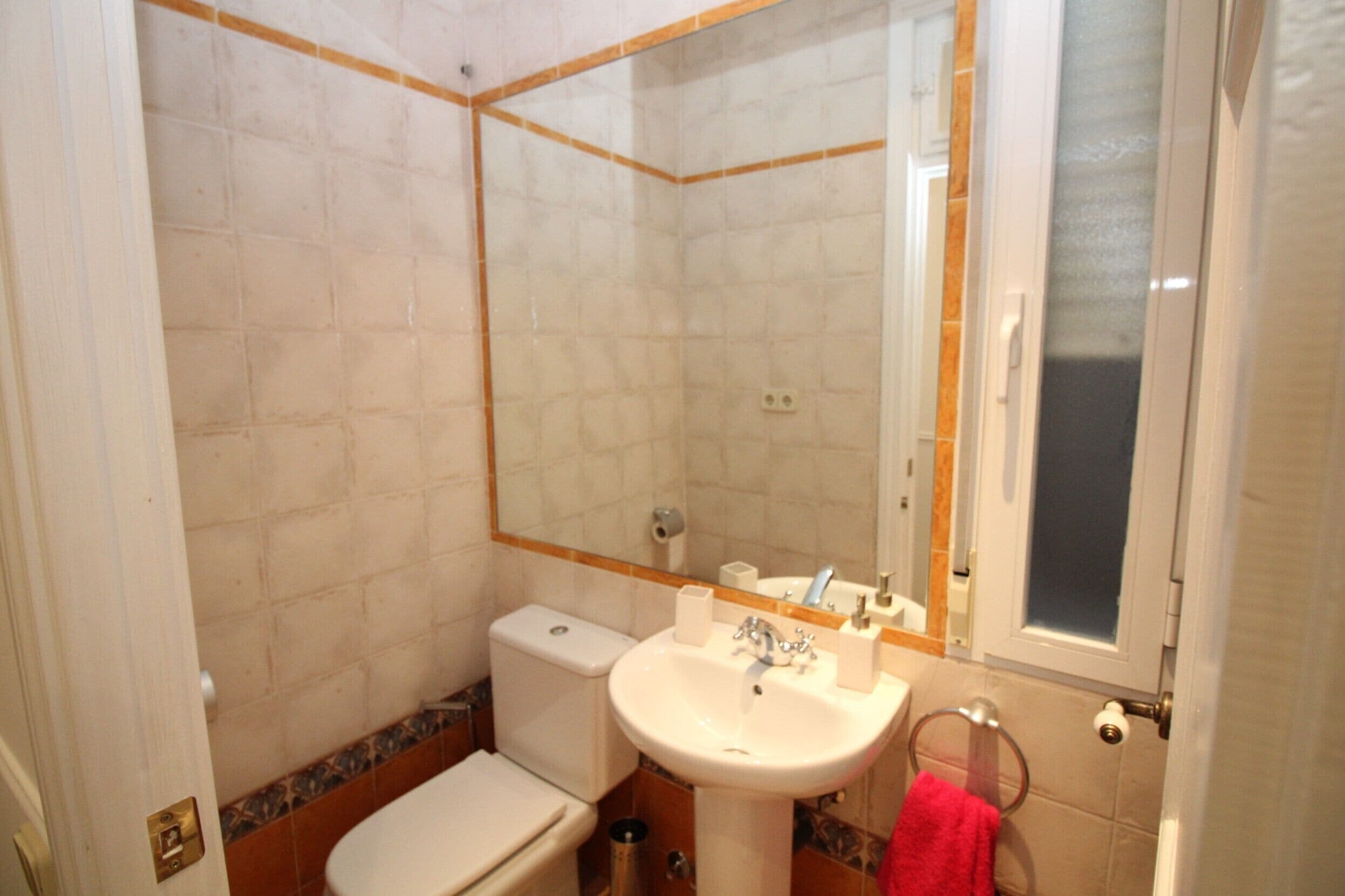 Un baño con inodoro, lavamanos y espejo.