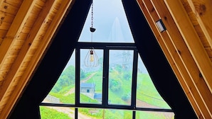 Une chambre à coucher avec un lit, une fenêtre et une vue sur un paysage verdoyant.