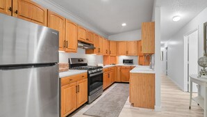Una cocina moderna con armarios de madera, electrodomésticos de acero inoxidable y una isla central.