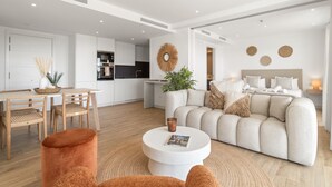 A modern living room with a sofa, a coffee table, and a dining area with chairs.