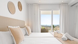 A hotel room with two beds, a balcony with a view, and a large window with curtains.