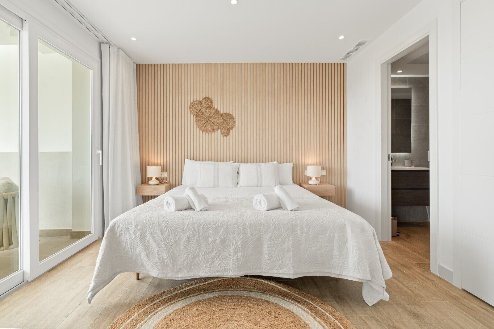 Een moderne slaapkamer met een groot bed, een wand van houten panelen en uitzicht naar buiten.