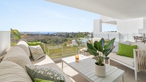 A modern outdoor living area with a sofa, a dining table, and a potted plant.