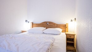 A bedroom with a wooden headboard, two bedside tables, and a bed with white bedding.