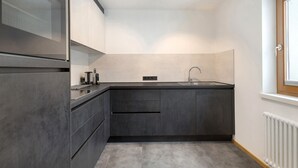A modern kitchen with dark cabinetry, a stainless steel range hood, and a window with a view.