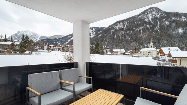 A balcony with a view of snow-covered mountains and a town.