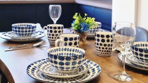 Een eettafel gedekt met blauw-witte borden, kommen en bekers, compleet met bestek en wijnglazen.
