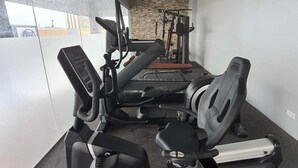 A gym with cardio equipment, weight machines, and a wall-mounted air conditioning unit.