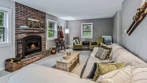A living room with a brick fireplace, a sofa, a coffee table, and two armchairs. - House on Private Acres with Fire Pit, Quechee (Quechee)